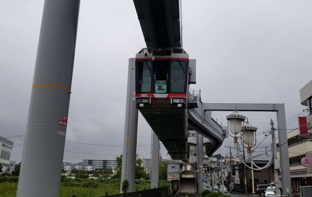 走っている大船モノレール　銀色の車体に2本の赤いライン
