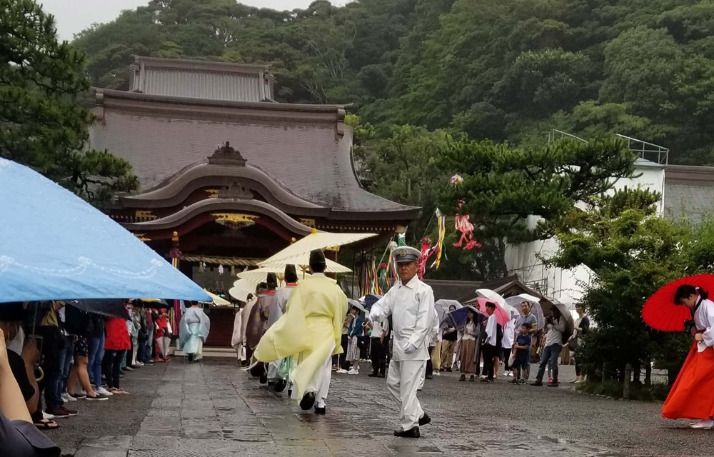 七夕祭りで舞殿に向かう神職たち 雨なので和傘を刺している