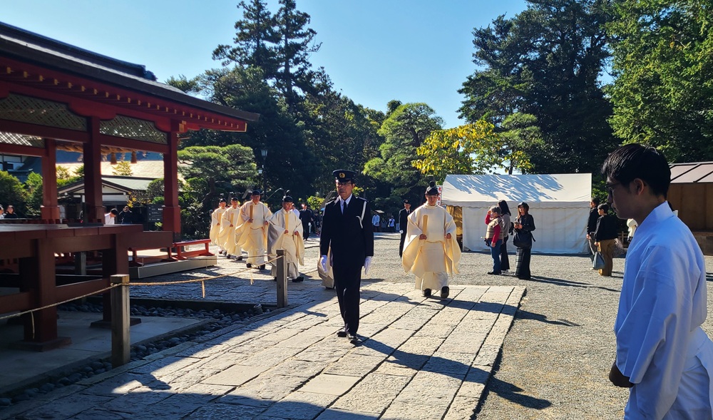 舞殿の横を通り本殿に向かう神職たち